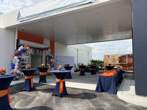 Outdoor event space set up with high-top tables and balloon decor for a grand opening