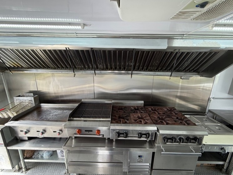 Like-new commercial kitchen interior of a 2022 Ford F59 food truck for sale in Pasco County FL showing full cooking line and stainless equipment