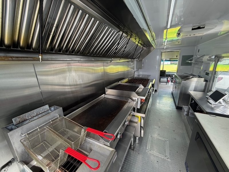 Full commercial cooking line inside a 2022 Ford F59 food truck showing 40lb deep fryer, flat top griddle, and 8-burner gas range – Florida