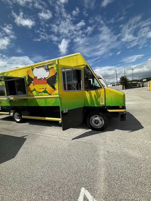 Driver side exterior of a 2022 Ford F59 food truck for sale in Pasco County Florida with tropical green and yellow vinyl wrap