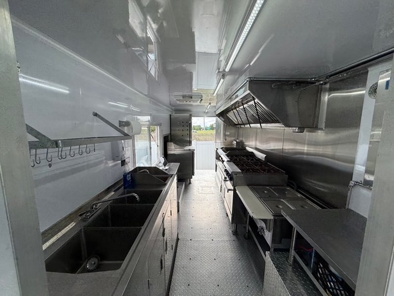 Full kitchen interior of a 2022 Ford F59 food truck for sale in Pasco County FL with 12-foot hood, 3-compartment sink, and stainless prep surfaces