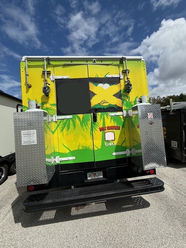 Rear exterior of a 2022 Ford F59 food truck with tropical vinyl wrap, dual 100lb propane tanks in secure box, and rear entry doors – Pasco County FL