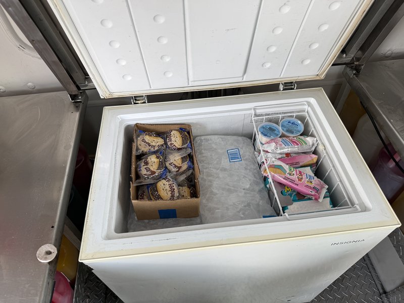 Chest freezer stocked with novelty ice cream and ice cream cups inside a frozen treats truck for sale in Florida