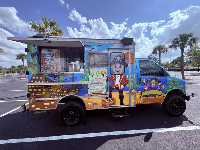 Passenger-side service window of a 1997 Chevrolet Express 3500 shaved ice truck for sale in Tampa, FL — open-air ordering setup