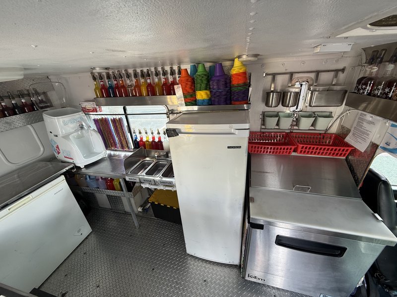 High-capacity multi-bottle syrup pump station and snow cone cup rack inside a shaved ice truck for sale in Tampa Bay, Florida