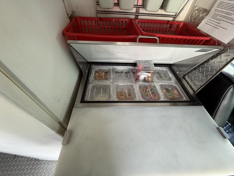 Stainless topping bar and prep station with insert bins inside a shaved ice and snow cone truck for sale in Tampa, FL